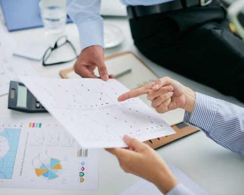 Hands of financial managers pointing at document